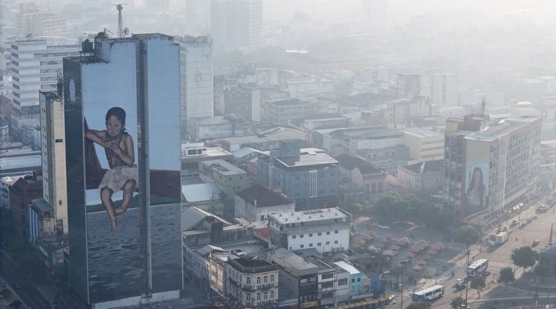 A drone view shows a mural on a building as smoke from Amazon wildfires and a burning landfill hangs over Manaus, Brazil, October 8, 2026. REUTERS/Bruno Kelly