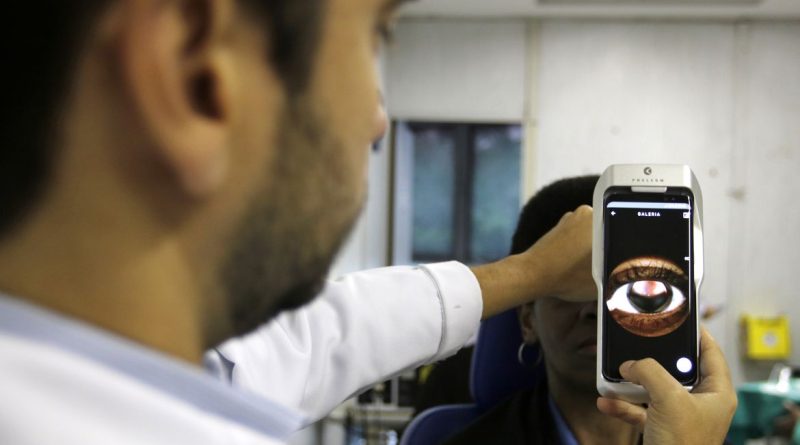 O Dr. Flávio Medina realiza exame de fundo de olho com um retinógrafo portátil,